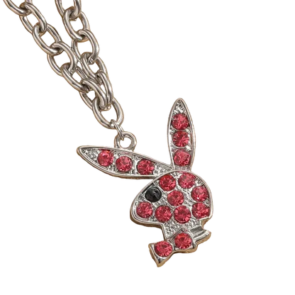 A silver-tone bunny pendant necklace embellished with red rhinestones, resting on a textured beige fabric background.
