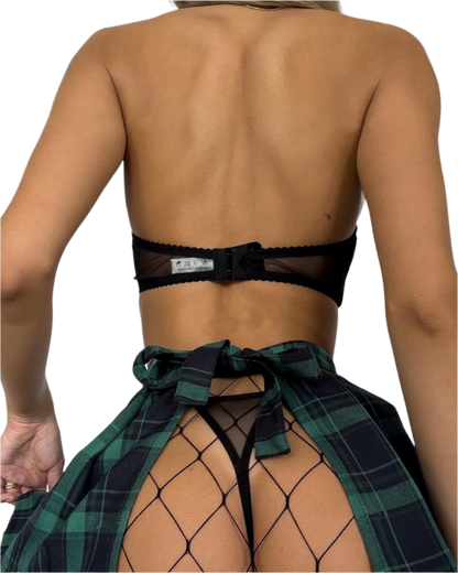 Person wearing a black bra and green plaid sarong on a plain background