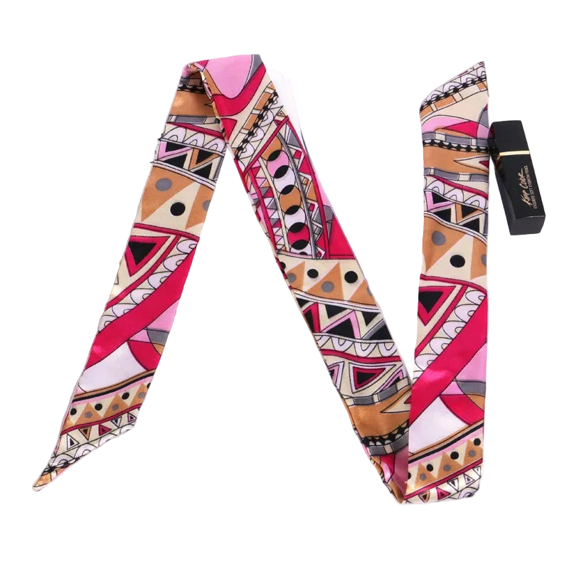 Colorful patterned scarf on a white surface with a magazine and lipstick.