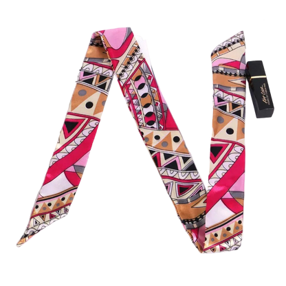 Colorful patterned scarf on a white surface with a magazine and lipstick.