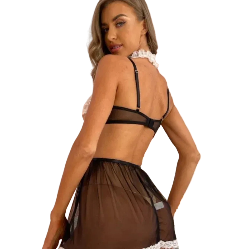 Woman wearing a black lace lingerie set in a softly lit room with pink curtains.