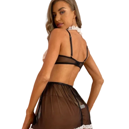 Woman wearing a black lace lingerie set in a softly lit room with pink curtains.