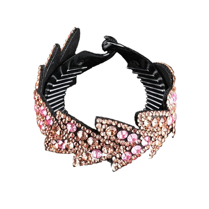A black hair claw clip embellished with pink and rose gold rhinestones, shown on a reflective black background.