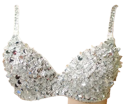A close-up of a silver rhinestone-embellished bralette displayed on a beige mannequin torso against a warm peach background.