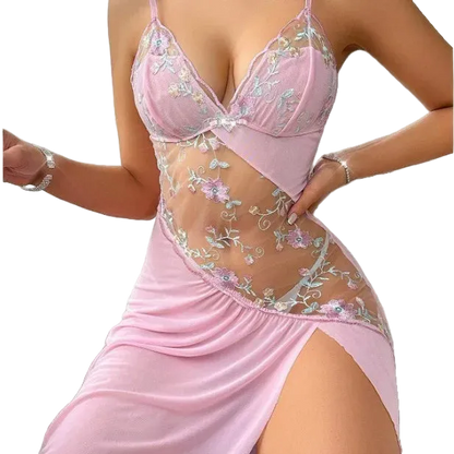 A woman wearing a light pink lingerie chemise with floral embroidered lace panels and sheer mesh details, shown against a plain white background.