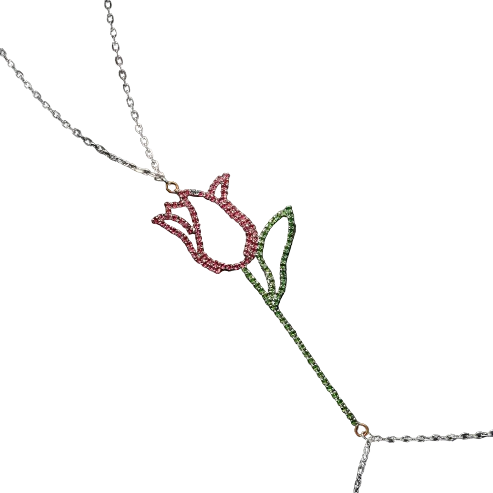 A silver-toned lariat necklace featuring a tulip pendant with a pink rhinestone flower head and a green rhinestone stem and leaves, displayed on a dark textured background.