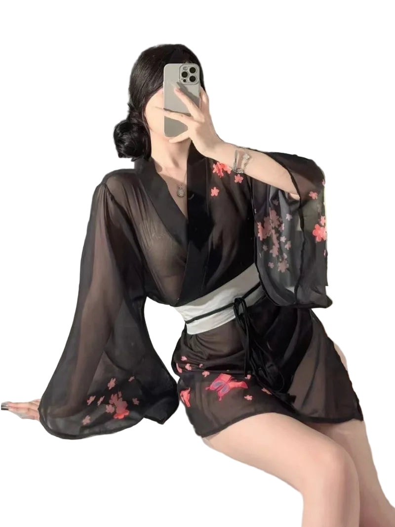 Person wearing a black sheer kimono with floral embroidery sitting on a bed.