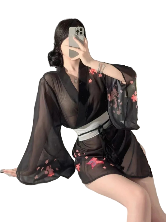 Person wearing a black sheer kimono with floral embroidery sitting on a bed.