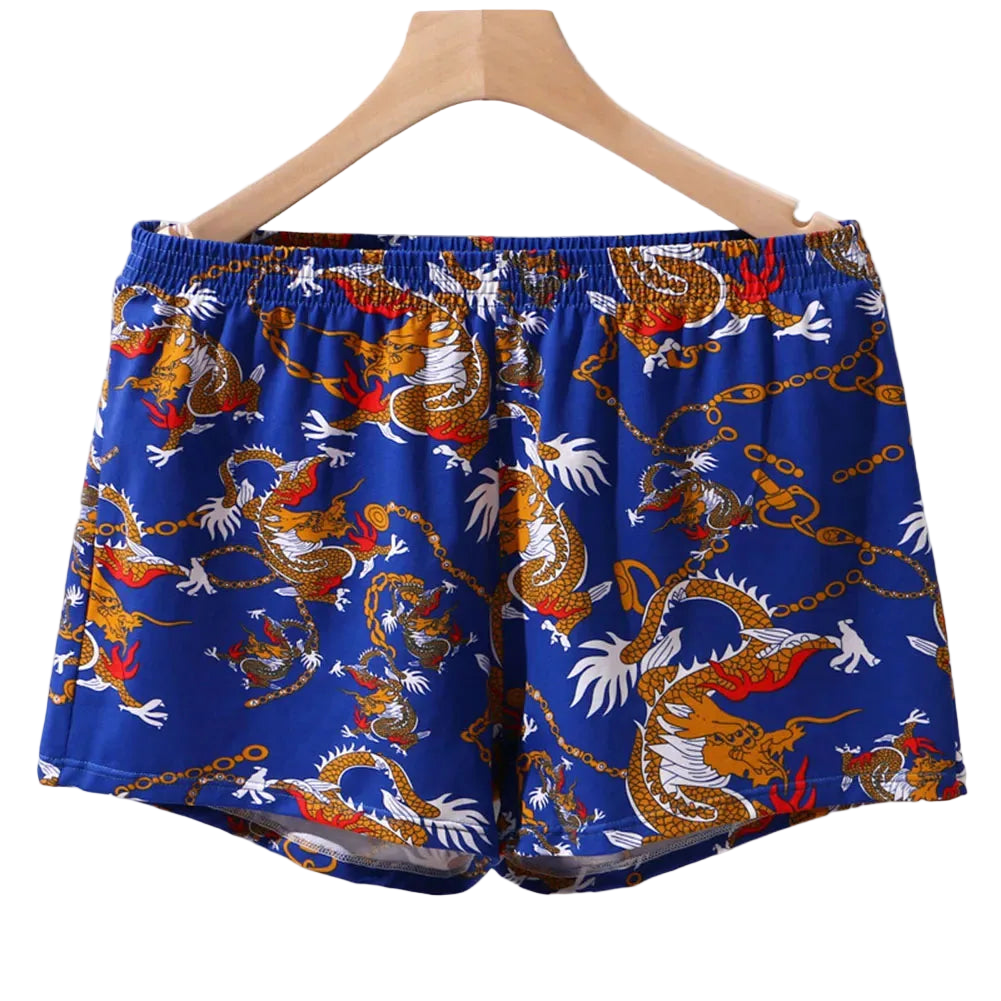 Blue shorts with dragon pattern on a hanger against a white background