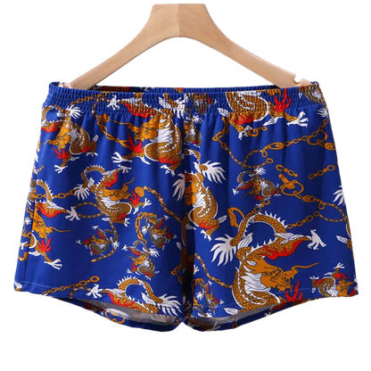 Blue shorts with dragon pattern on a hanger against a white background