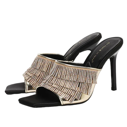 A pair of black open-toe high-heeled mule sandals with wide straps covered in cascading rhinestone fringe, shown on a clean white background.