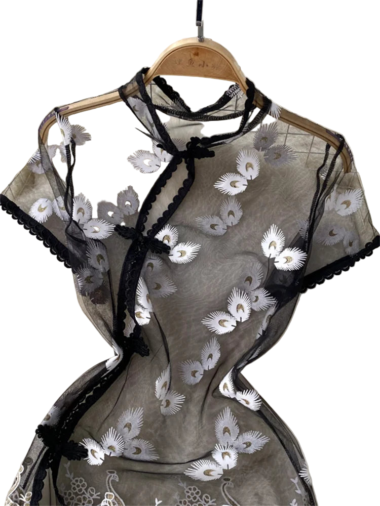 Translucent top with floral embroidery on a hanger against a tiled wall.