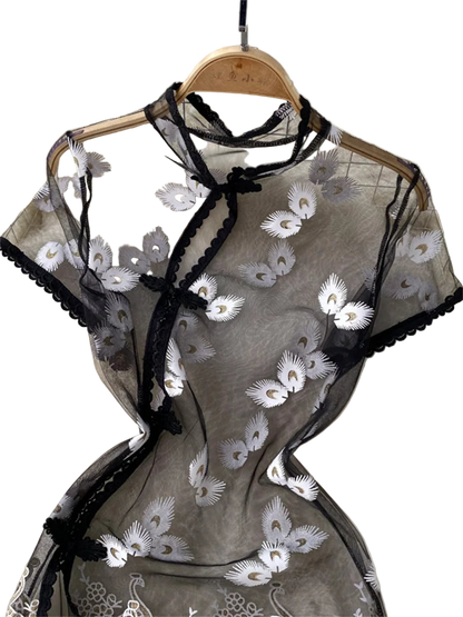 Translucent top with floral embroidery on a hanger against a tiled wall.