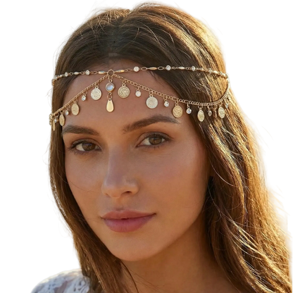 Woman wearing a gold headband with coins and beads on a beach.