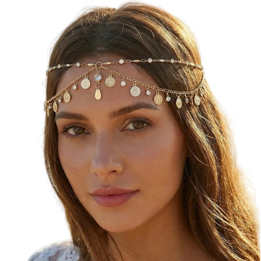 Woman wearing a gold headband with coins and beads on a beach.