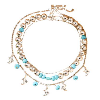 Stack of silver and turquoise beaded necklaces on a beige surface