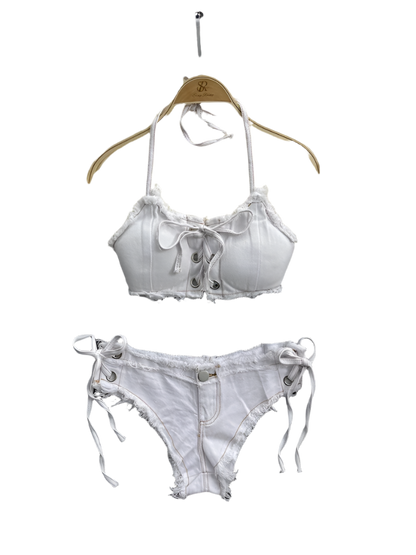 White denim bra and panties set on a textured surface with a pearl-handled bag and flowers in the background.
