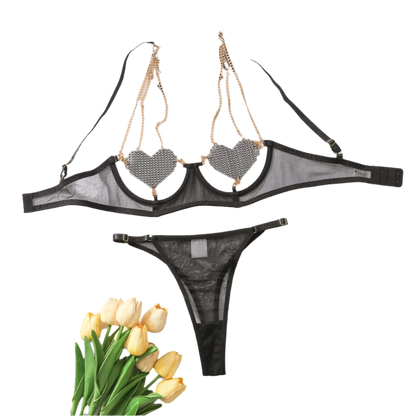 A  lingerie set with sparkling embellishments. The top features heart-shaped accents and is connected with gold chains, paired with a matching bottom.