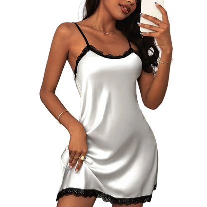 Woman wearing a white satin nightgown with black lace trim, holding a phone.