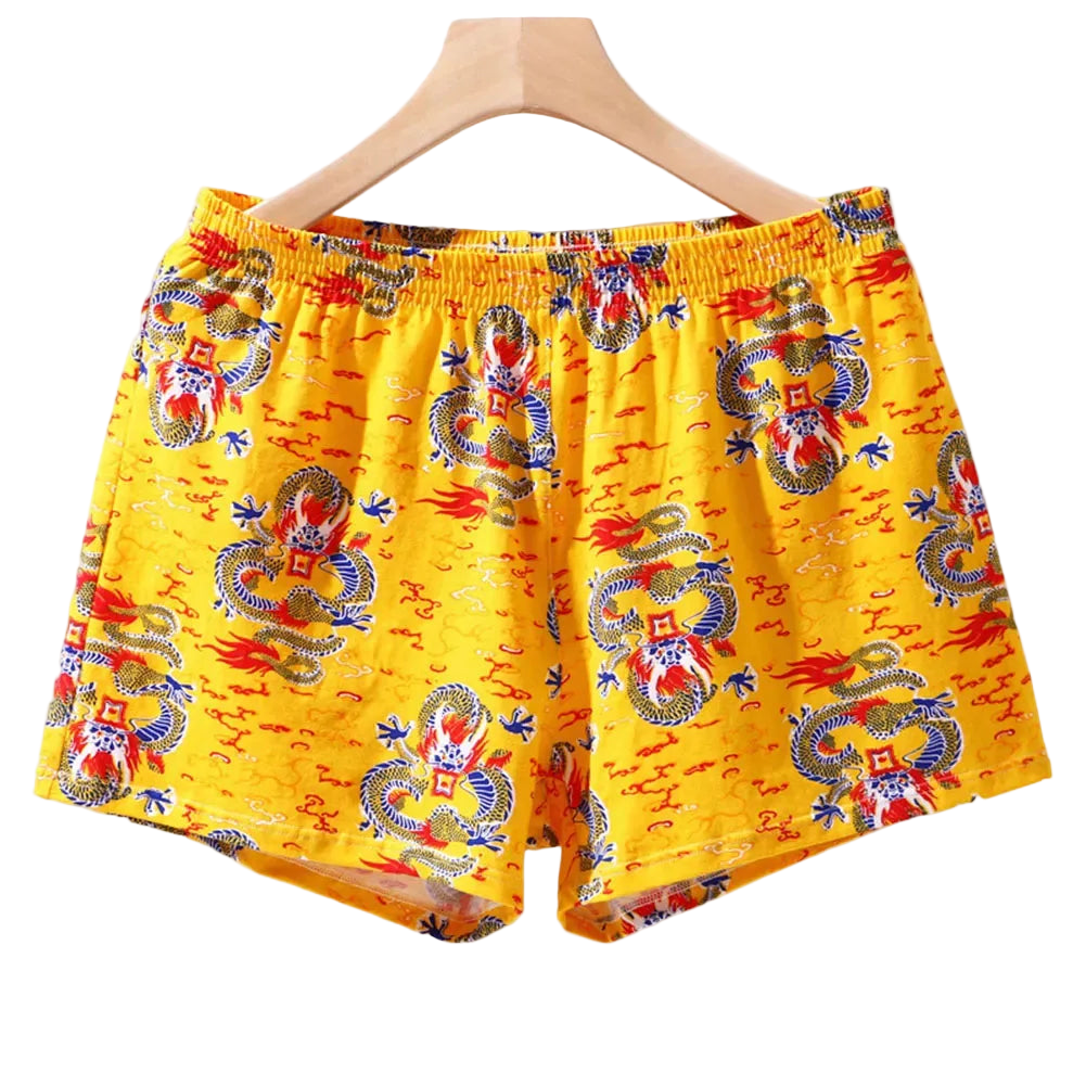 Yellow boxer shorts with dragon pattern on a hanger against a white background