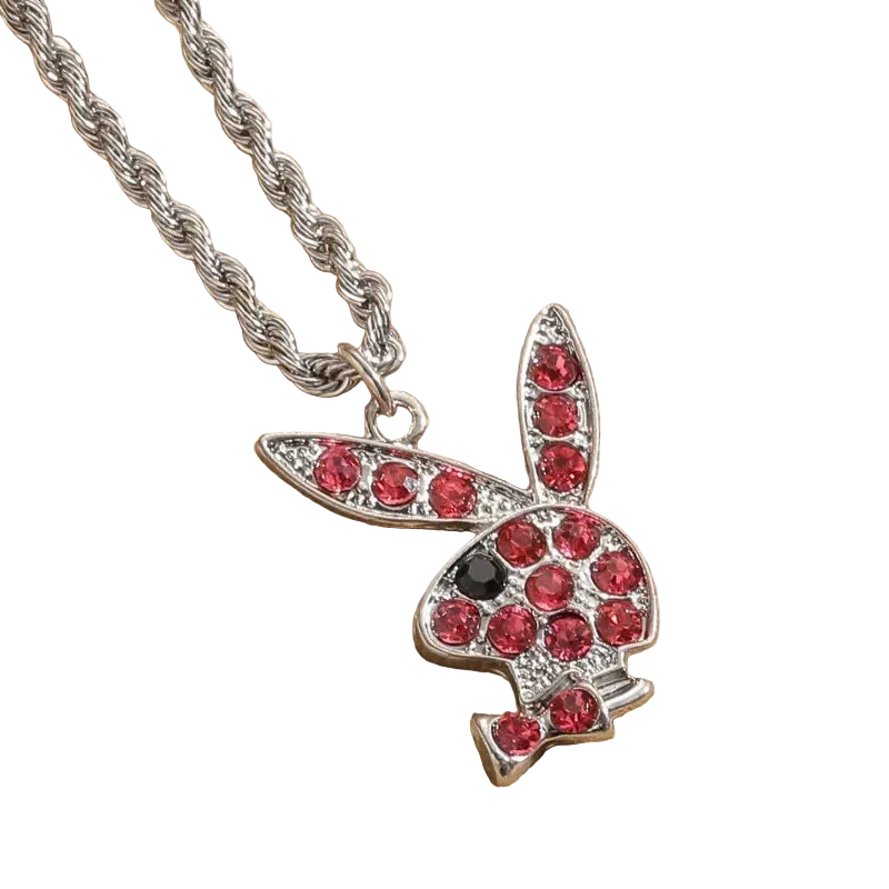 A silver bunny pendant necklace paved with red gemstones, featuring a small black gemstone for the eye, resting on a textured beige fabric background.