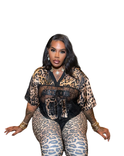 Woman sitting on a bench wearing a leopard print outfit with a black top.