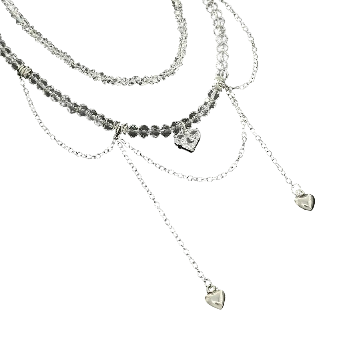 A layered silver necklace set featuring a beaded top layer, delicate chain dangles, and three small heart charms, displayed on a black background.