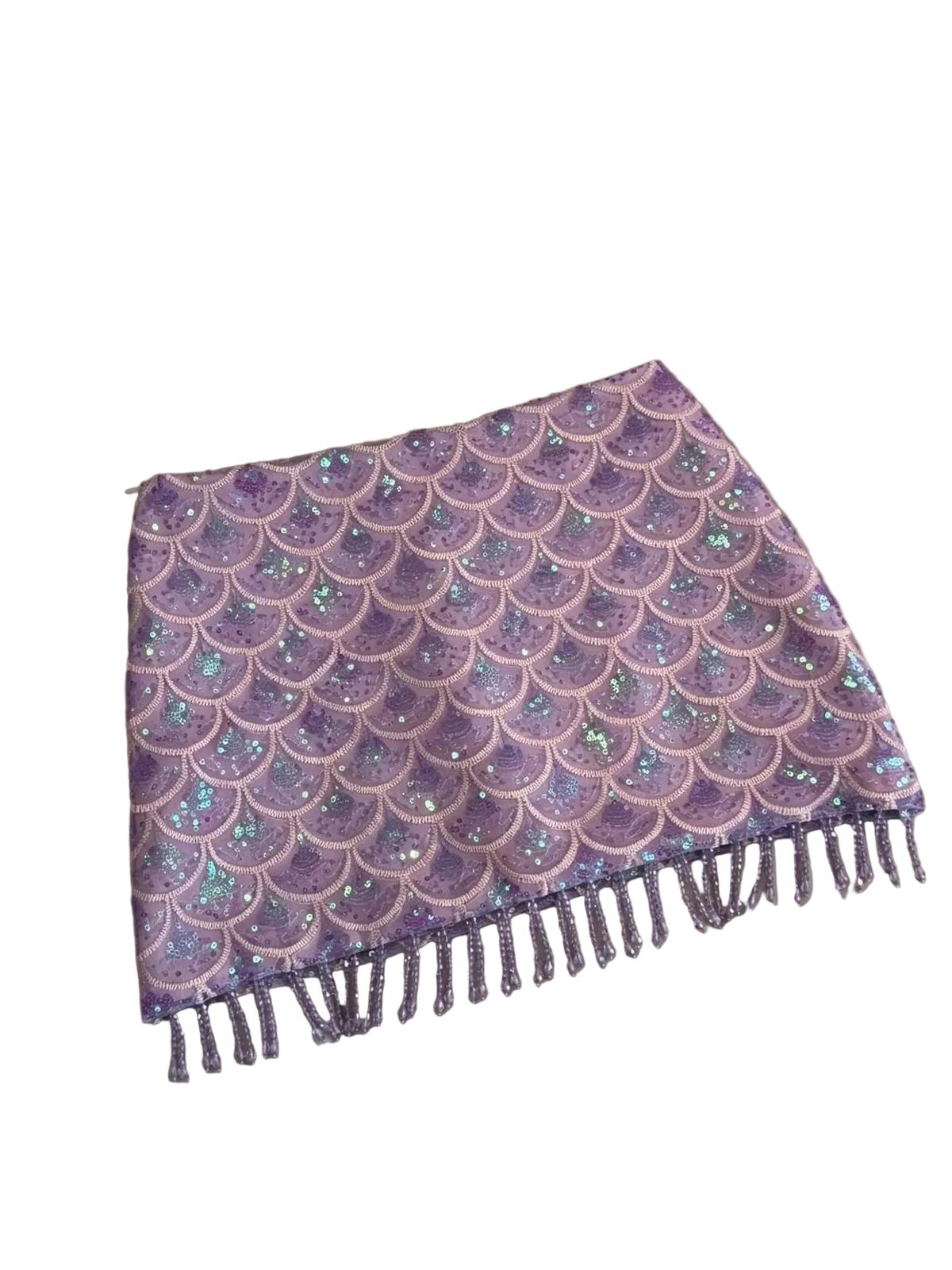 A lavender and pink mermaid scale sequin scarf with fringe, laid flat on a beige leather sofa.