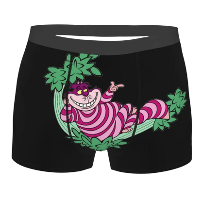 boxer shorts featuring the Cheshire Cat design from Alice in Wonderland, with glowing turquoise eyes and distinctive grinning teeth illuminated against a dark background.