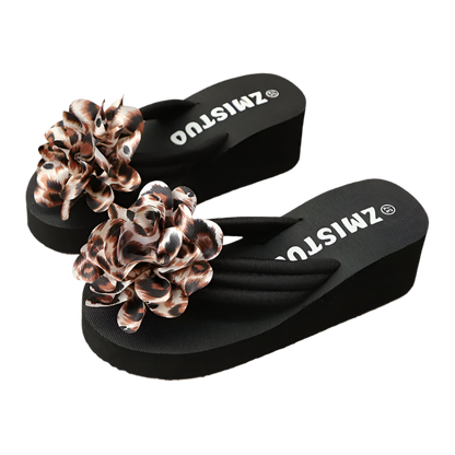 Black flip-flops with leopard print flowers on a textured surface