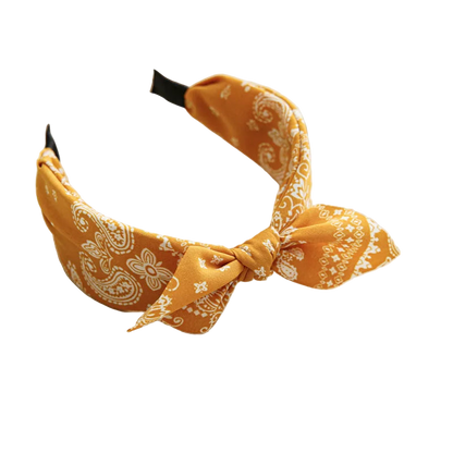 Yellow patterned headband on a white tray with a cup and coaster in the background