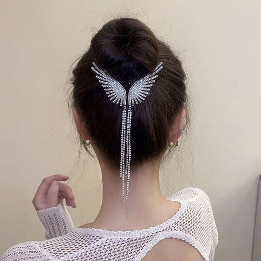 Elegant hair accessory featuring a wing-shaped rhinestone design that cascades down the back of the head. The piece forms a Y-shape with crystalline stones arranged in a delicate pattern against dark hair.