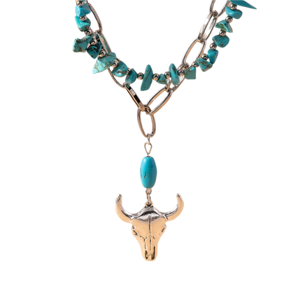 Necklace with turquoise stones and bull skull pendant on a beige background