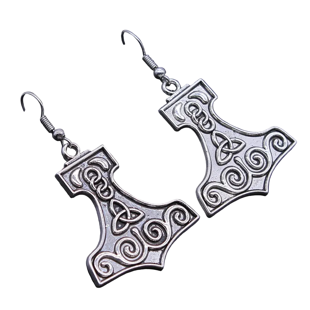 A pair of silver-toned drop earrings shaped like Mjolnir, featuring Celtic knotwork details, displayed on a dark textured surface.