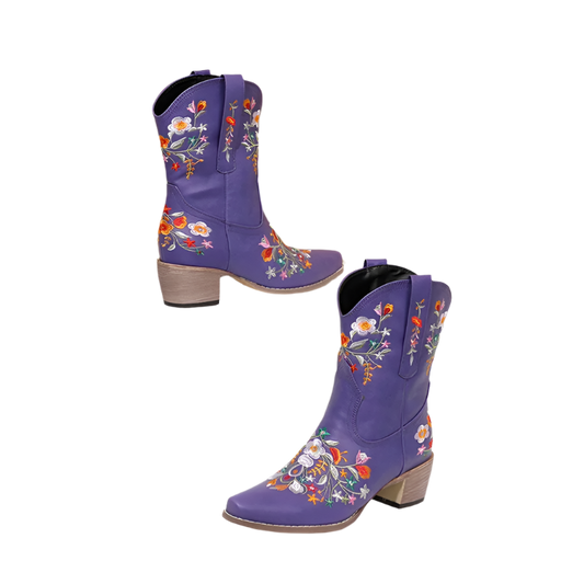 Purple cowboy boots with floral embroidery on a white surface and beige background