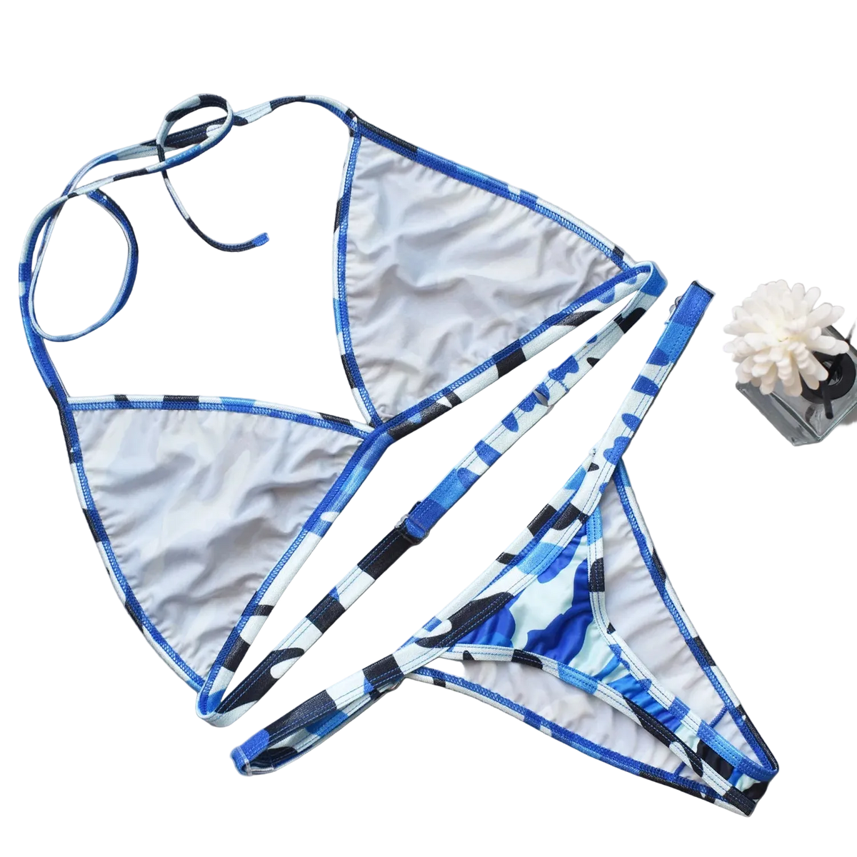 Blue and white patterned bikini set on a gray surface with decorative elements.