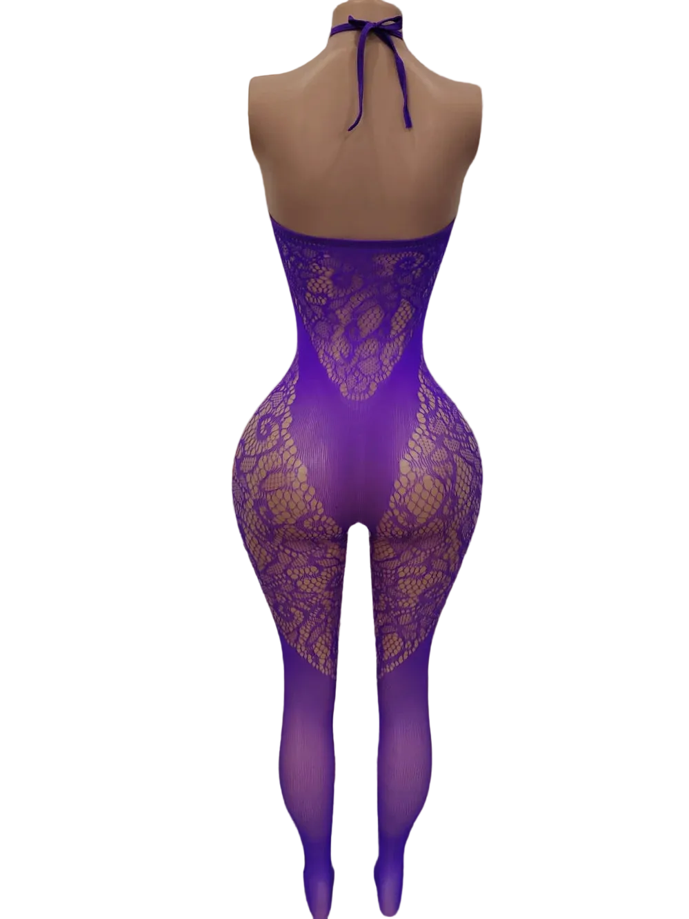 A mannequin wearing a purple lace bodysuit with matching sheer tights, shown from the back in a softly lit bedroom with a bed, lamp, and curtains in the background.