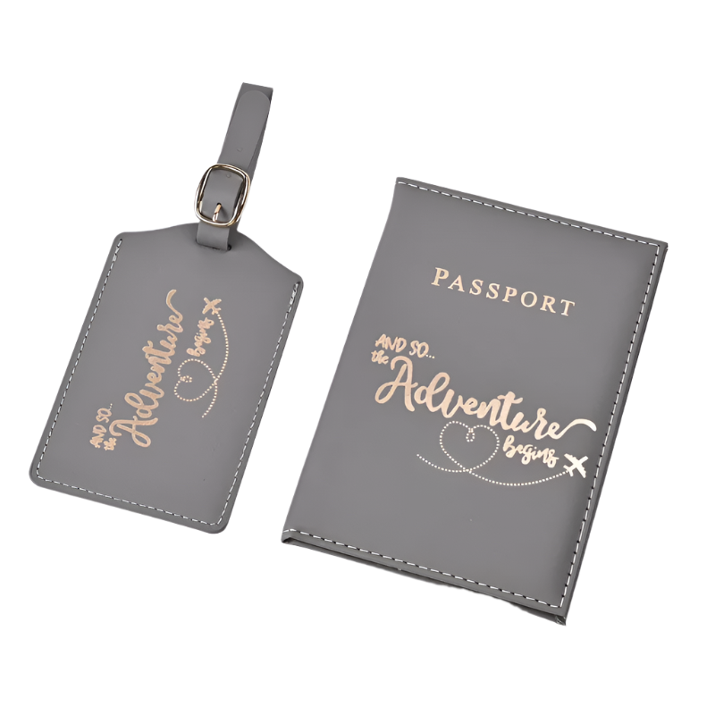 A passport holder and luggage tag set with the phrase "And so the adventure begins" in elegant script. The design is sleek and stylish, perfect for travel.