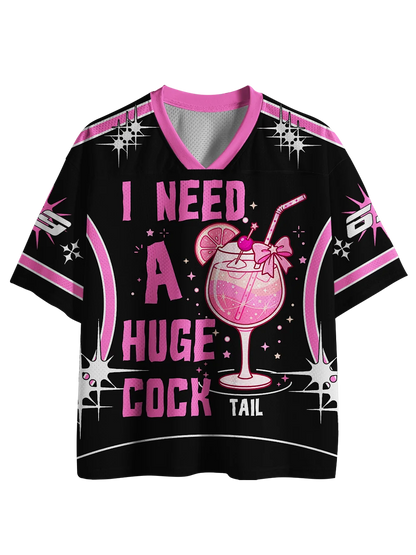 A black short-sleeve V-neck t-shirt with a pink and white graphic print. The design features a pink cocktail illustration in the center, surrounded by the text 'I NEED A HUGE COCK TAIL' in bold pink lettering, with sparkles and star accents.