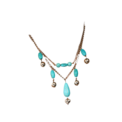 Necklace with turquoise beads and silver heart pendant on a white top