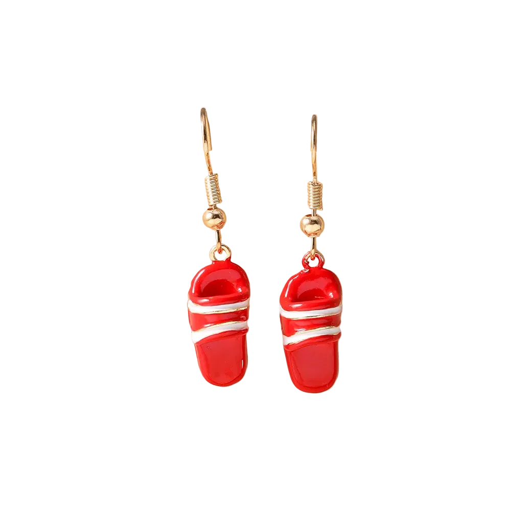 A pair of red and white slide-shaped drop earrings with gold hooks, displayed on a beige jewelry stand.