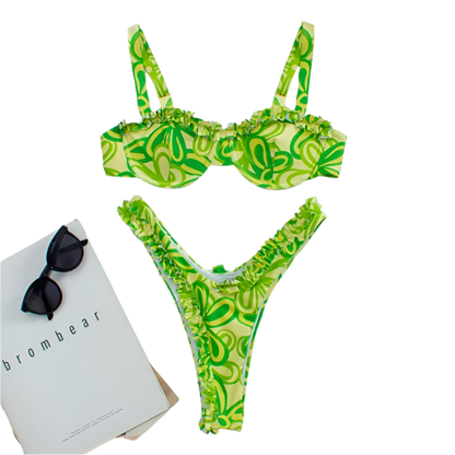 A vibrant bikini set with a green floral pattern and pink ruffle trim. The top has structured cups and adjustable straps, while the bottom features a high-cut design.