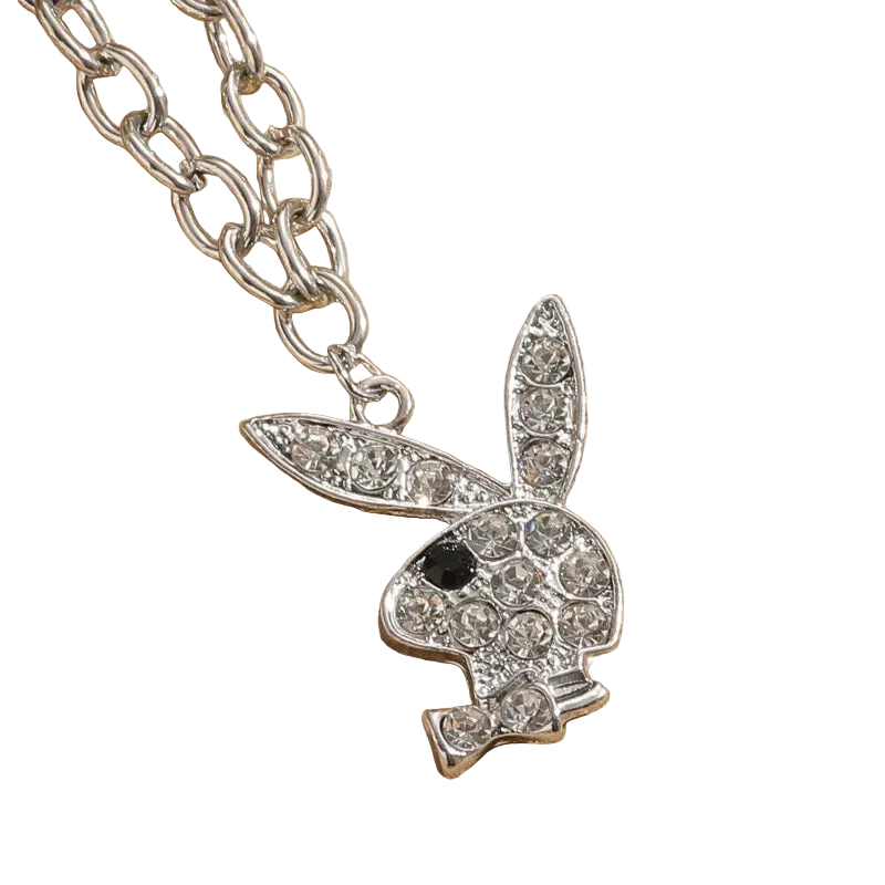 A silver-tone bunny pendant necklace, styled like the Playboy bunny, encrusted with clear rhinestones and featuring a small black eye, shown on a textured beige background.