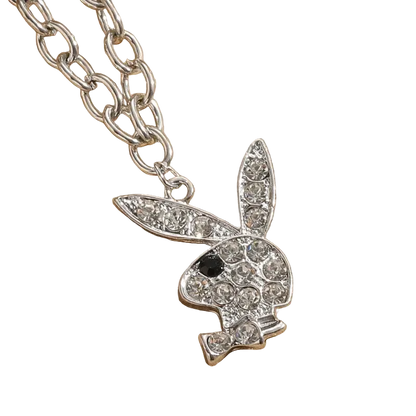 A silver-tone bunny pendant necklace, styled like the Playboy bunny, encrusted with clear rhinestones and featuring a small black eye, shown on a textured beige background.