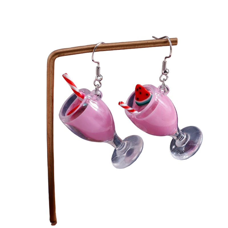 Pink cocktail glass earrings with a cherry on top on a stand against a dark background