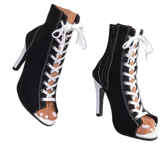 Black high-heeled shoes with white laces on a neutral background