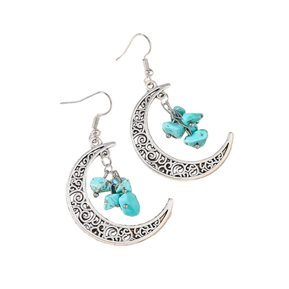 Silver earrings with turquoise stones on a textured beige surface
