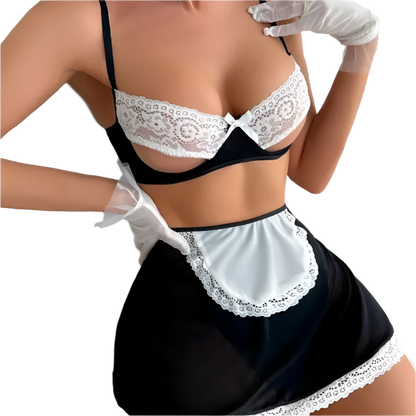 Person wearing a black and white lace lingerie set with a red rose on a bed.