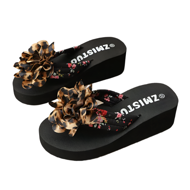 Black sandals with floral and leopard print straps on a textured surface