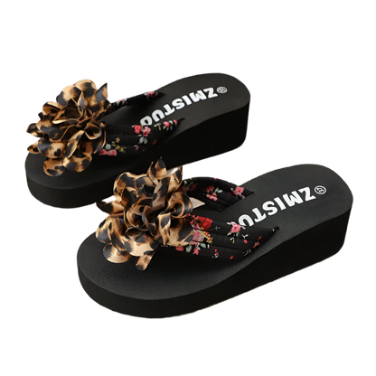 Black sandals with floral and leopard print straps on a textured surface